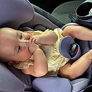 Cecilia is registered to the contest to win money with this photo: baby, car_seat, child, infant, yellow_clothing, sucking_hands, chubby_legs, purple_seat, car_interior, seat_belt, cute, adorable, relaxed, young_child, infant_girl, portrait, baby_pose, car_trip, child_safety, comfortable
