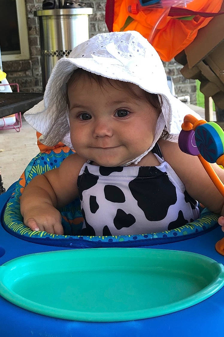 Madison is registered to the contest to win money with this photo: baby, baby_toddler_clothing, baseball_cap, blue, cap, cheek, child, dishware, facial_expression, fashion_accessory, fun, happy, headwear, human, joy, leisure, person, recreation, sitting, skin