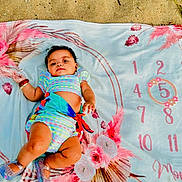 Hope joined the competition — help win amazing prizes! baby, infant, blanket, sand, floral_pattern, colorful_clothing, shoes, bracelet, outdoor, child, portrait, cute, lying_down, summer, nature, skin, feet, hand, expression, playful