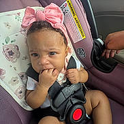 Alani is registered to the contest to win money with this photo: baby, child, car_seat, pink_bow, headband, car_interior, seatbelt, hand, fingers, person, infant, cute, sitting, clothing, safety, child_safety, portrait, closeup, expression, indoors