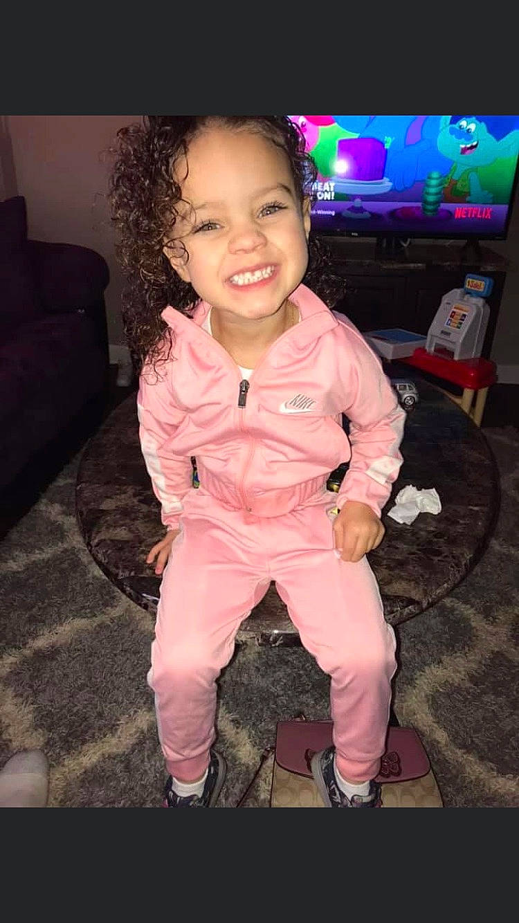 Zariah is registered to the contest to win money with this photo: baby_toddler_clothing, cheek, child, couch, eye, face, flash_photography, flooring, fun, happy, head, human_body, joy, magenta, person, pink, shoe, sleeve, smile, t_shirt