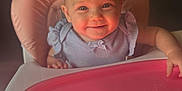 Lola joined the competition — help win amazing prizes! baby, high_chair, smiling, child, indoor, pink, face, person, cute, happy, infant, clothing, tray, seat, portrait, young_child, cute_expression, light, shadow, background