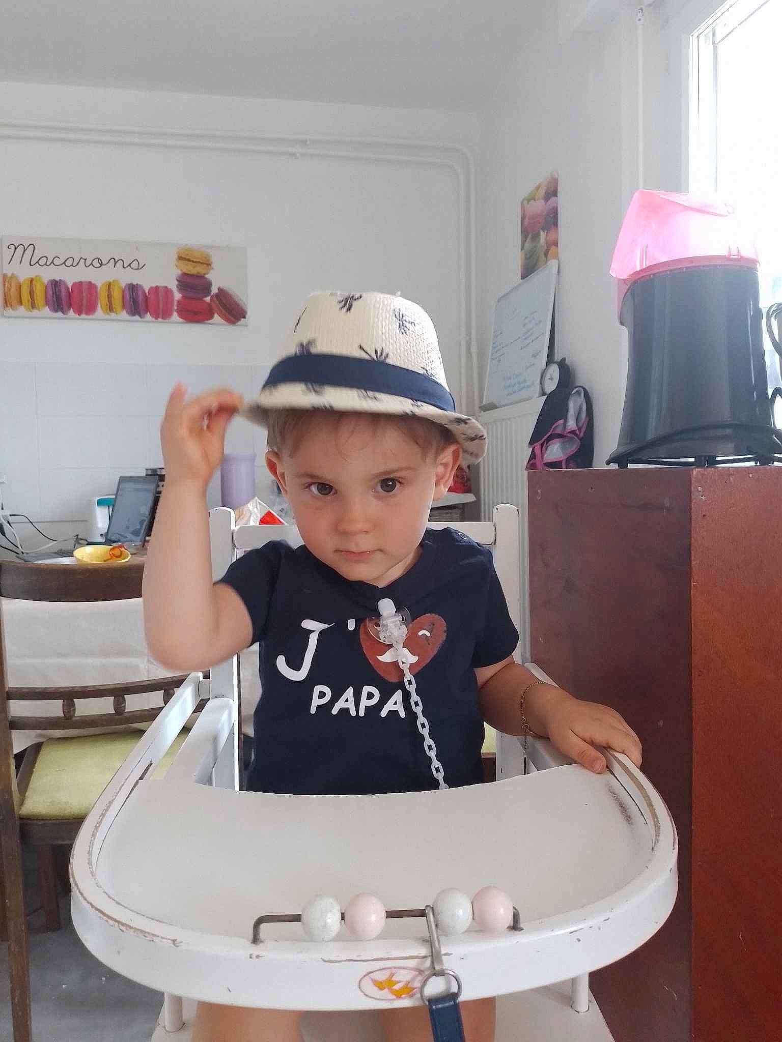 Anael participe au concours pour gagner de l'argent avec cette photo : baby, baby_toddler_clothing, baseball_cap, cap, child, cleanliness, curtain, fashion_accessory, fun, hat, human_body, lamp, lampshade, person, picture_frame, room, shorts, sitting, sleeve, t_shirt