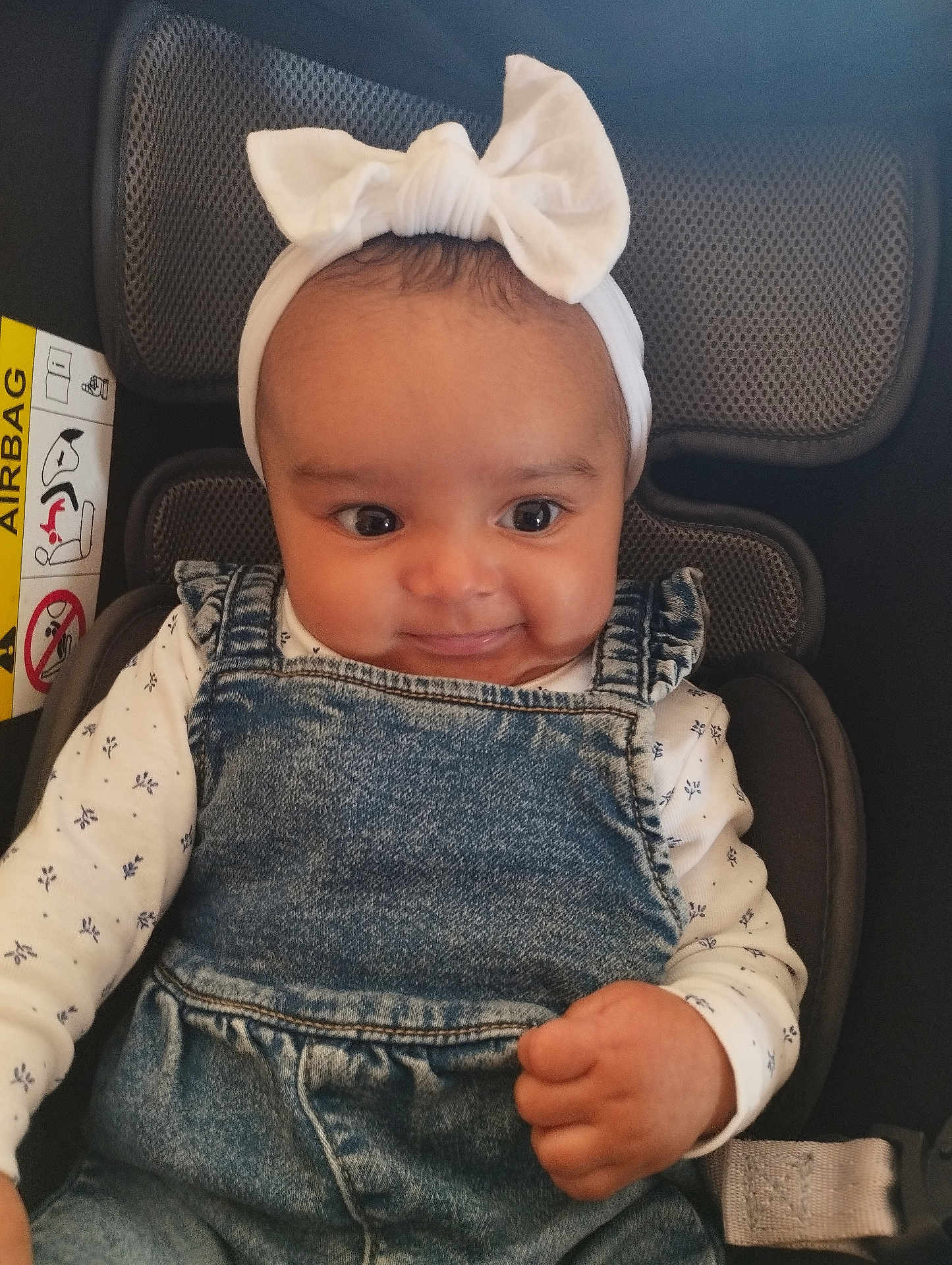 Ewenn a rejoint le concours — aidez-le/la à gagner de superbes lots ! baby, child, headband, bow, denim, overalls, car_seat, smile, face, infant, clothing, cute, portrait, happy, young_child, sitting, hand, indoors, seatbelt, person