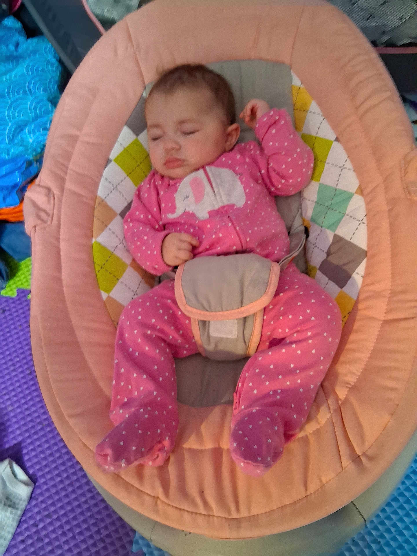 Elie is registered to the contest to win money with this photo: baby, sleeping, onesie, pink_clothing, elephant_design, baby_rocker, colorful_padding, play_mat, soft_toys, infant, child, indoors, resting, cute, cozy, footed_pajamas, baby_gear, face, person, peaceful