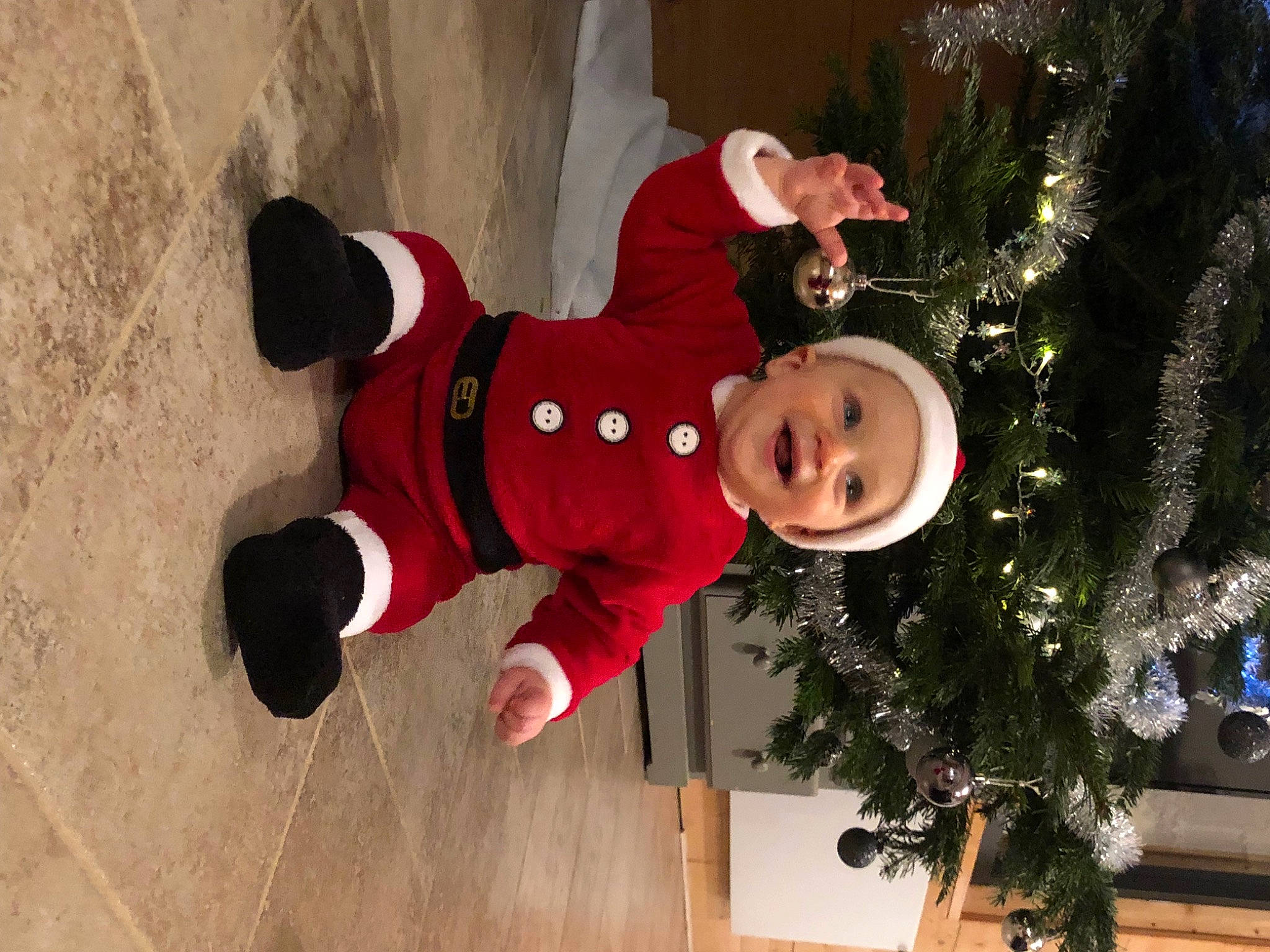 Lilian participe au concours pour gagner de l'argent avec cette photo : carmine, christmas, christmas_decoration, christmas_eve, christmas_ornament, christmas_tree, conifer, event, fun, happy, hat, headwear, holiday, interior_design, jacket, ornament, person, plant, smile, toddler