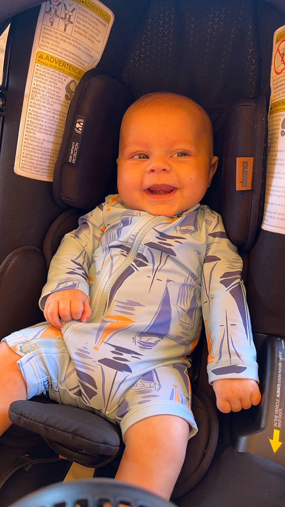 Ryder is registered to the contest to win money with this photo: baby, baby_toddler_clothing, car_seat, cheek, child, comfort, cool, finger, fun, happy, head, joy, knee, mouth, orange, person, skin, smile, thigh, thumb