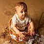 baby, child, wicker_basket, lace_outfit, curly_hair, wooden_floor, cotton_flowers, hands, cute, portrait, expression, sitting, indoor, soft_lighting, natural_texture, innocent, small, person, closeup, infant