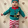 adorable, baby, blanket, blue_eyes, child, christmas, clothing, costume, cute, face, festive, hat, holiday, indoors, infant, lying_down, red_green, smile, star_pattern, striped_pants