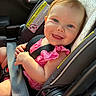 baby, child, car_seat, safety_belt, pink_clothing, smiling, blue_eyes, infant, car_interior, seatbelt, happy, cute, portrait, young_child, secure, sunlight, closeup, baby_girl, car_safety, infant_seat