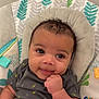 baby, infant, smiling, face, hand, curly_hair, onesie, blanket, seat, patterned_fabric, toucan, colorful, cute, comfort, child, portrait, happy, indoor, closeup, young
