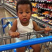 A'Mazi joined the competition — help win amazing prizes! aisle, barefoot, child, clothing, floor, grocery_store, holding, indoor, metal_cart, packaged_goods, person, retail, serious_expression, shopping, shopping_cart, store, supermarket, tank_top, toddler, young_child