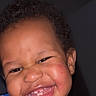 A'Mazi is registered to the contest to win money with this photo: baby, cheeks, child, closeup, curly_hair, cute, dark_background, emotion, expression, face, happy, head, indoors, joy, person, portrait, skin, smiling, teeth, toddler