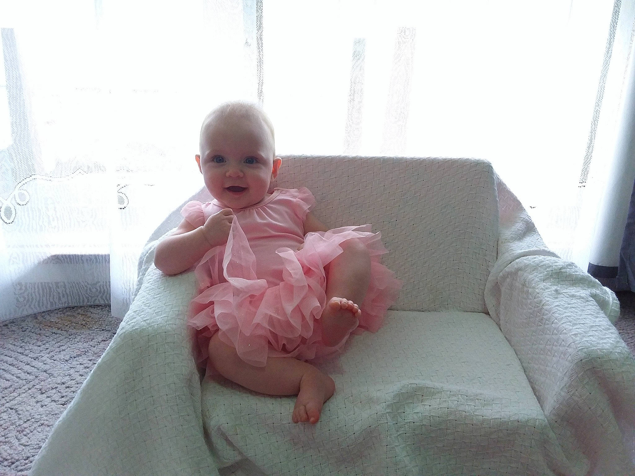 Lily joined the competition — help win amazing prizes! baby, baby_toddler_clothing, barefoot, comfort, couch, curtain, face, flooring, foot, head, knee, linens, person, shoulder, skin, sleeve, smile, thigh, toddler, window