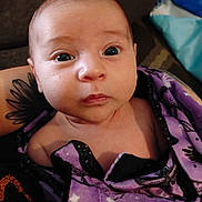 Alyana is registered to the contest to win money with this photo: baby, infant, blanket, purple, face, eyes, tattoo, person, portrait, curious, child, skin, cozy, wrapped, young, cute, indoors, human, sleepwear, newborn