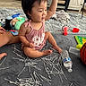 Kai Yumi joined the competition — help win amazing prizes! toddler, child, baby, sitting, smiling, indoor, living_room, playroom, pink_outfit, dark_hair, face, portrait, toy, cotton_swabs, water_bottle, basketball, rug, blanket, furniture, playful