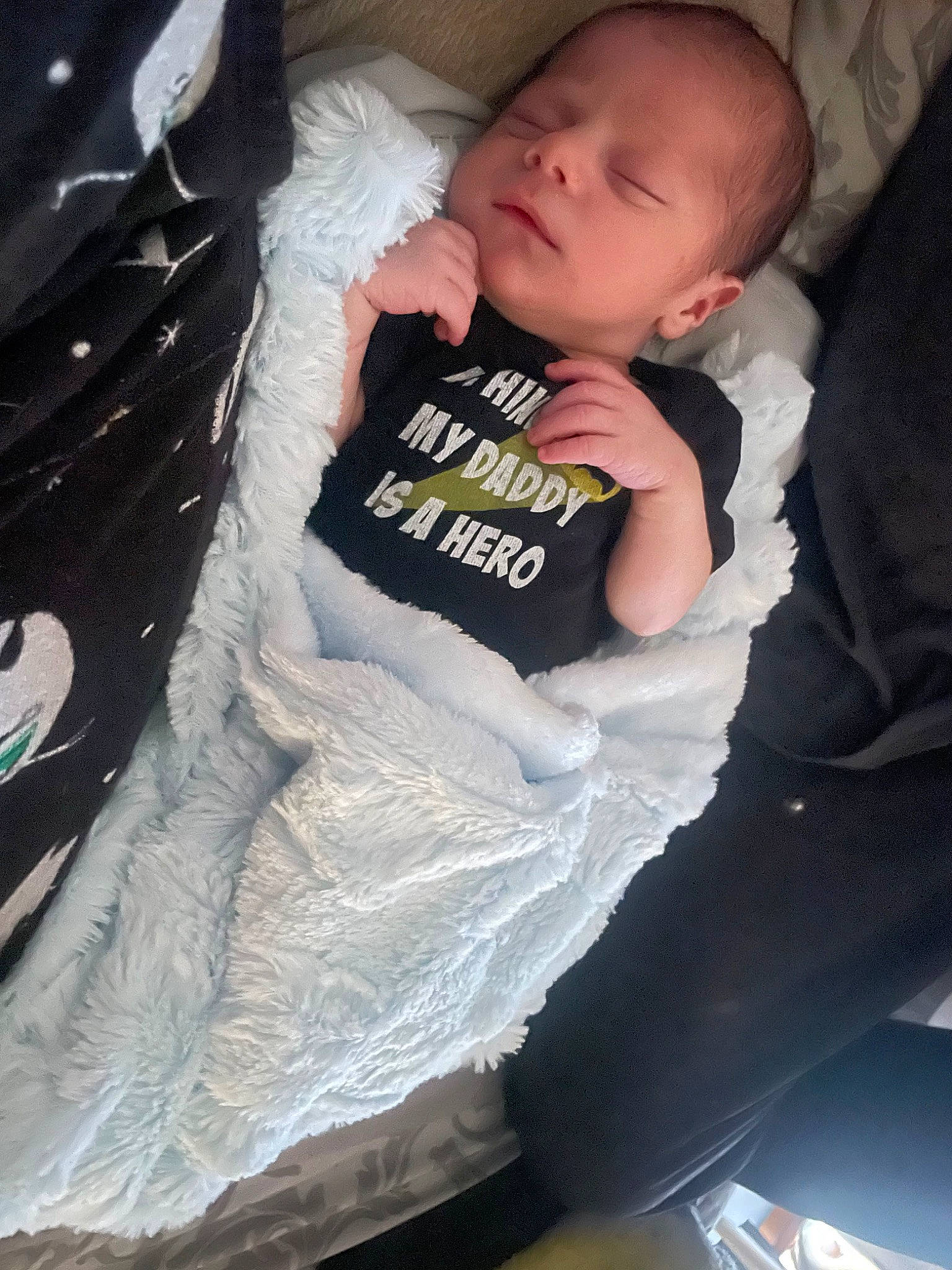 Damian is registered to the contest to win money with this photo: baby, baby_carriage, baby_products, baby_toddler_clothing, car_seat, carmine, cheek, child, comfort, elbow, head, human_leg, lap, pattern, person, room, sitting, sleeve, t_shirt, thigh