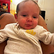 Kessler is registered to the contest to win money with this photo: american_flag, baby, blur, cabinet, casual, child, closeup, clothing, face, furniture, indoor, infant, legs, nike, person, tattoo, teddy_bear, toy, wall, white_outfit