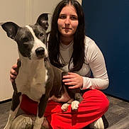 Nala a rejoint le concours — aidez-le/la à gagner de superbes lots ! dog, person, indoor, wood_floor, sitting, pet, white_shirt, red_pants, sneakers, gray_dog, portrait, long_hair, paw, door, blue_wall, flooring, human_face, animal_face, companionship, casual_clothing