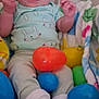 baby, infant, headband, bow, onesie, bunny_print, socks, plastic_eggs, easter_eggs, blanket, toy, hands, face, portrait, closeup, soft_texture, smiling, indoor, seated, cute