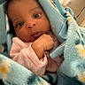 baby, blanket, blue_blanket, child, closeup, cozy, curious, cute, face, floral_pattern, hand, indoors, infant, newborn, pink_clothing, portrait, soft_texture, warm, wide_eyes, wrapped