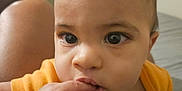 Brysan is registered to the contest to win money with this photo: baby, infant, child, face, hand, fingers, orange_clothing, blanket, indoors, portrait, curious, closeup, skin, eyes, mouth, person, young, cute, sleepwear, bedroom
