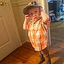 Jaxon joined the competition — help win amazing prizes! child, indoor, boy, plaid_shirt, cap, cowboy_boots, wooden_floor, door, curious, standing, brown_pants, short_sleeves, young_child, blurry_background, warm_lighting, casual_clothing, person, face, hat, portrait