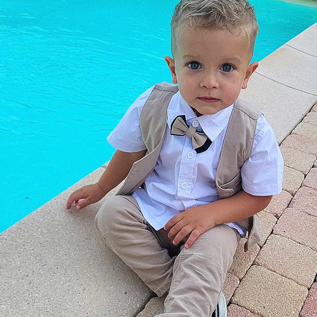 Malow participe au concours pour gagner de l'argent avec cette photo : big_eyes, blue_water, bow_tie, boy, brick_patio, child, concrete_edge, cute, fashion, outdoor, pool, portrait, short_hair, sitting, sneakers, summer, toddler, vest, water, white_shirt