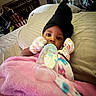 Malaya is registered to the contest to win money with this photo: baby, bottle, blanket, bed, crib, mittens, hat, milk, infant, sleeping_area, room, pillow, person, child, indoor, cozy, colorful, soft, cute, resting