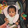 Malaya is registered to the contest to win money with this photo: baby, infant, car_seat, pacifier, hand, toy_rings, curly_hair, expression, cushion, clothing, green_shorts, white_shirt, child, indoor, person, seatbelt, pink, orange, teething_toys, adorable