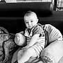 baby, child, dog, couch, cushion, indoor, pet, portrait, sitting, blanket, clothing, socks, furniture, relaxing, cute, comfort, black_and_white, home, face, person