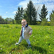 Lino a rejoint le concours — aidez-le/la à gagner de superbes lots ! toddler, child, smiling, outdoor, grass, field, dandelion, trees, blue_sky, clouds, jacket, sneakers, nature, sunny, happy, walking, greenery, casual_clothing, daytime, portrait