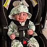 Zakari joined the competition — help win amazing prizes! baby, infant, child, car_seat, harness, mickey_mouse, pajamas, hat, portrait, sitting, wide_eyed, smiling, indoors, vehicle, safety_seat, black_background, clothing, toy, hands, photography