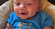 Zakari joined the competition — help win amazing prizes! baby, infant, child, smiling, portrait, blue_shirt, cushion, blanket, seated, indoor, close_up, face, eyes, mouth, light_skin, happy, cozy, textile, photography, adorable