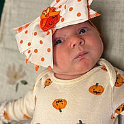 Poetri is registered to the contest to win money with this photo: baby, infant, face, headwear, bow, polka_dots, pumpkin, halloween, clothing, onesie, cute, expression, lying_down, blanket, soft_texture, orange, white, child, portrait, indoor