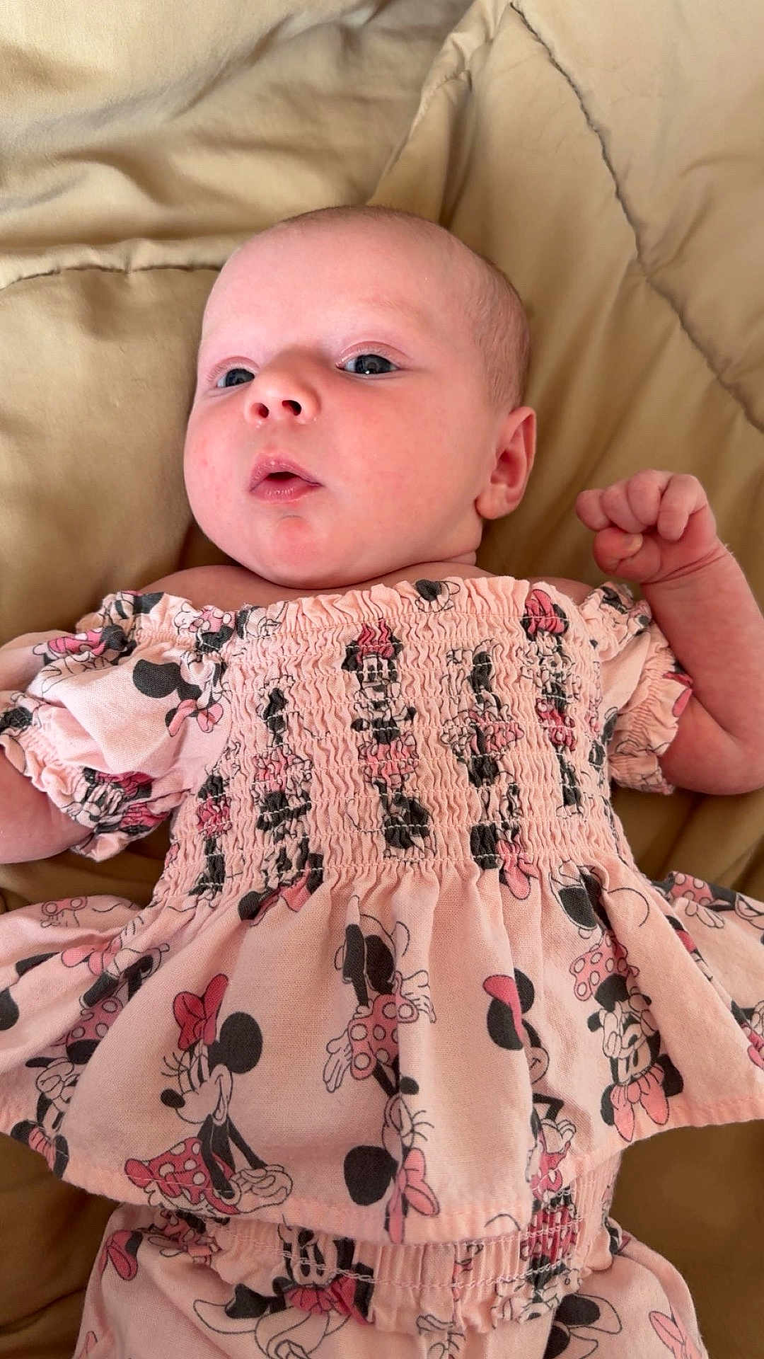 Poetri joined the competition — help win amazing prizes! baby, infant, child, pink_clothing, minnie_mouse, patterned_outfit, blanket, laying_down, cute, young_child, person, face, head, expression, raised_fist, small_hand, soft_texture, indoor, portrait, sleepwear