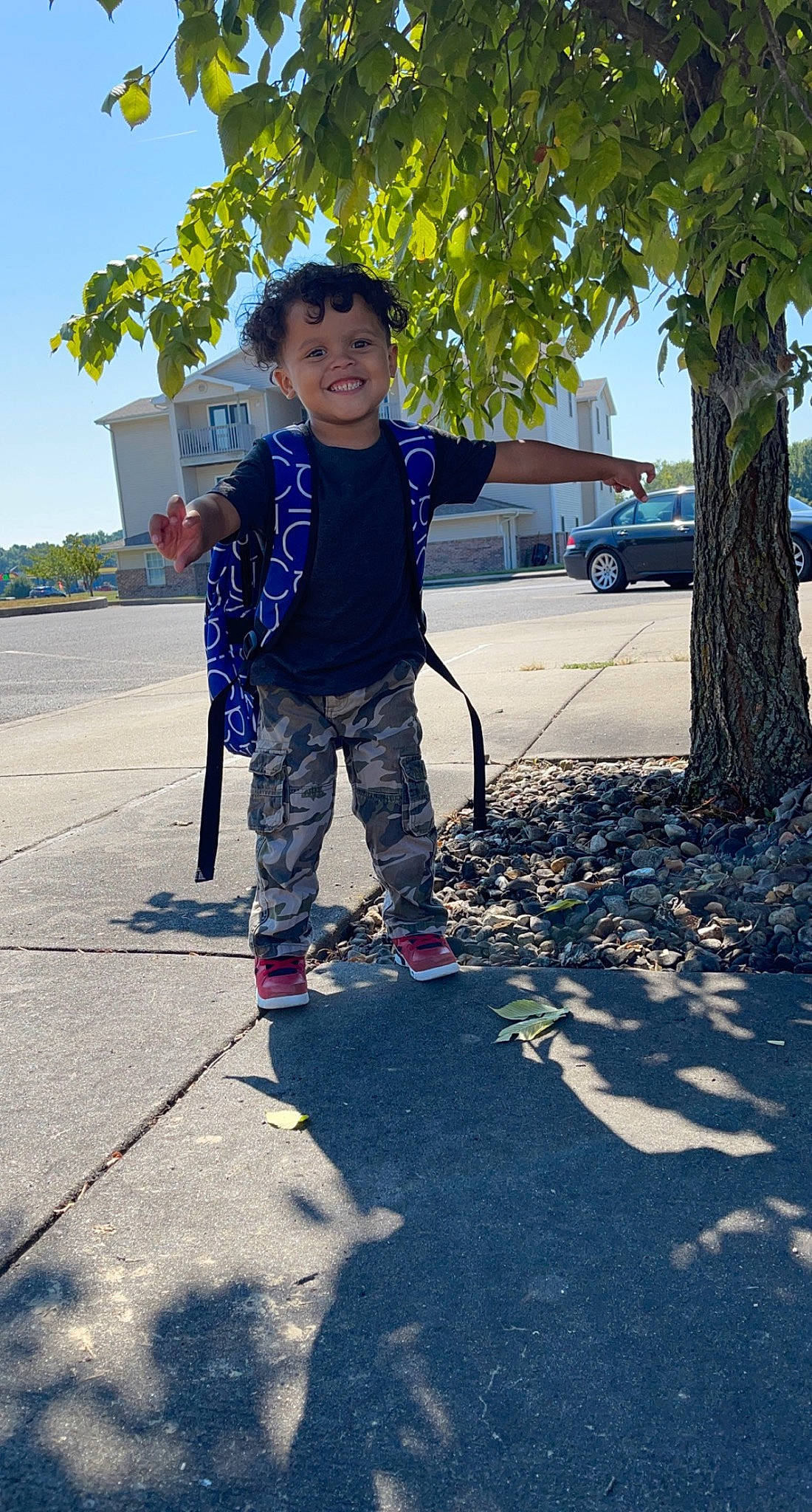 Prince is registered to the contest to win money with this photo: asphalt, city, denim, electric_blue, fun, happy, joy, leaf, leisure, pedestrian, person, plant, recreation, road, road_surface, sidewalk, sky, smile, t_shirt, toddler