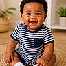baby, smiling, striped_clothing, sitting, white_socks, curly_hair, indoor, woven_mat, plant, happy, child, portrait, cute, young_child, toddler, face, cheerful, cozy, room, casual