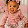 Lakenya is registered to the contest to win money with this photo: baby, child, infant, smiling, pink_bow, headband, pink_clothing, ruffled_sleeves, patterned_pants, socks, curly_hair, happy, portrait, sitting, nursery, soft_blanket, cute, indoors, young_child, warm_lighting