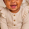 baby, child, smiling, headband, bow, curly_hair, sitting, carpet, plush_toy, teddy_bear, neutral_colors, long_sleeve, onesie, cute, portrait, indoors, happy, infant, soft_texture, cozy