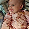 baby, child, infant, smiling, portrait, indoors, sitting, reclining, pink_outfit, giraffe_pattern, pajamas, blanket, pillow, couch, home, face, eyes, blonde_hair, happy, closeup