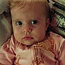 Myla joined the competition — help win amazing prizes! baby, child, infant, portrait, face, eyes, looking_at_camera, serious, pink_outfit, clothing, zipper, necklace, couch, cushion, indoor, sitting, close_up, blonde_hair, photography, cozy