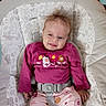 baby, baby_seat, brown_hair, child, closeup, floral_pattern, furniture, happy, indoor, infant, long_sleeves, pants, pink_clothing, portrait, rocker, safety_harness, seated, smiling, tufted_hair, white_socks