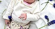 Myla joined the competition — help win amazing prizes! baby, infant, headband, purple, flower, blanket, outdoor, grass, cute, clothing, white_shirt, patterned_pants, socks, lying_down, nature, portrait, young_child, soft_light, relaxed, headwear