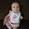 Myla joined the competition — help win amazing prizes! baby, child, infant, bib, pink_clothing, socks, couch, upholstery, face, eyes, expression, person, sitting, indoors, texture, fabric, cute, small_child, portrait, apparel
