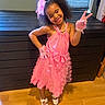 child, girl, pink_dress, gloves, smile, peace_sign, curly_hair, headband, pearl_necklace, white_shoes, wooden_floor, cabinet, window, indoor, fashion, happy, posing, accessories, playful, confident