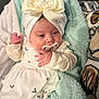 Emma is registered to the contest to win money with this photo: baby, blanket, bow, child, clothing, cozy, cute, face, floral_pattern, hand, headband, indoor, infant, newborn, pacifier, peaceful, portrait, resting, sleepwear, soft_texture