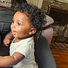 Marcellus joined the competition — help win amazing prizes! adult, blanket, child, clothing, couch, cozy, curly_hair, fireplace, furniture, happy, home_interior, indoors, person, printed_pants, sitting, smiling, standing, toddler, white_onesie, wood_floor