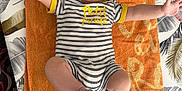 Kurtys participe au concours pour gagner de l'argent avec cette photo : arms_stretched, baby, child, clothing, cute, fabric, face, feet, head, indoors, infant, lying_down, orange, patterned_background, person, smiling, striped_clothing, summer, tablecloth, towel