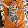 Kurtys participe au concours pour gagner de l'argent avec cette photo : baby, infant, towel, striped_clothing, arms_stretched, lying_down, orange, tablecloth, patterned_background, feet, head, face, child, person, cute, smiling, summer, indoors, fabric, clothing